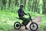 Helmeted rider on forest trail sits stationary on electric dirt bike during daytime Helmeted rider on forest trail sits stationary on electric dirt bike during daytime
