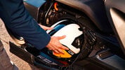 The storage compartment of BMW's CE-04 electric scooter showing a helmet being stowed The storage compartment of BMW's CE-04 electric scooter showing a helmet being stowed